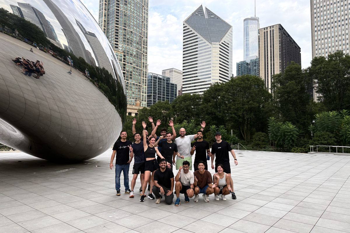Part of the team waving in front of the Bean in Millennium Park
