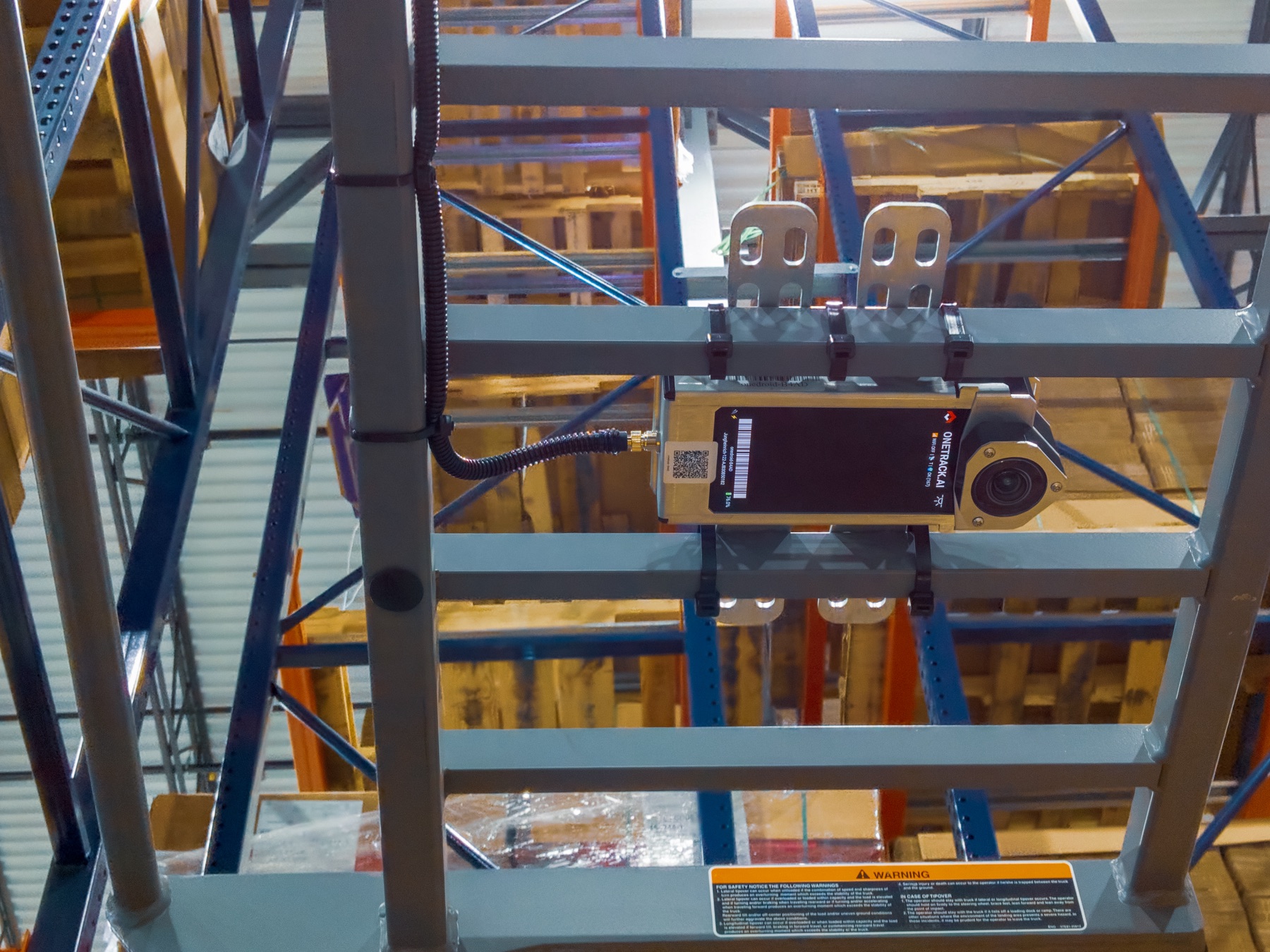 A OneTrack sensor mounted on a forklift's overhead guard, in a racked aisle