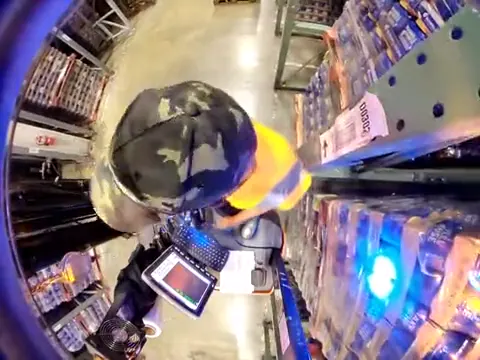Overhead still: a stand-up forklift backing toward a rack