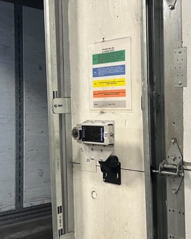 A stationary OneTrack sensor mounted on a dock door frame beside an open trailer